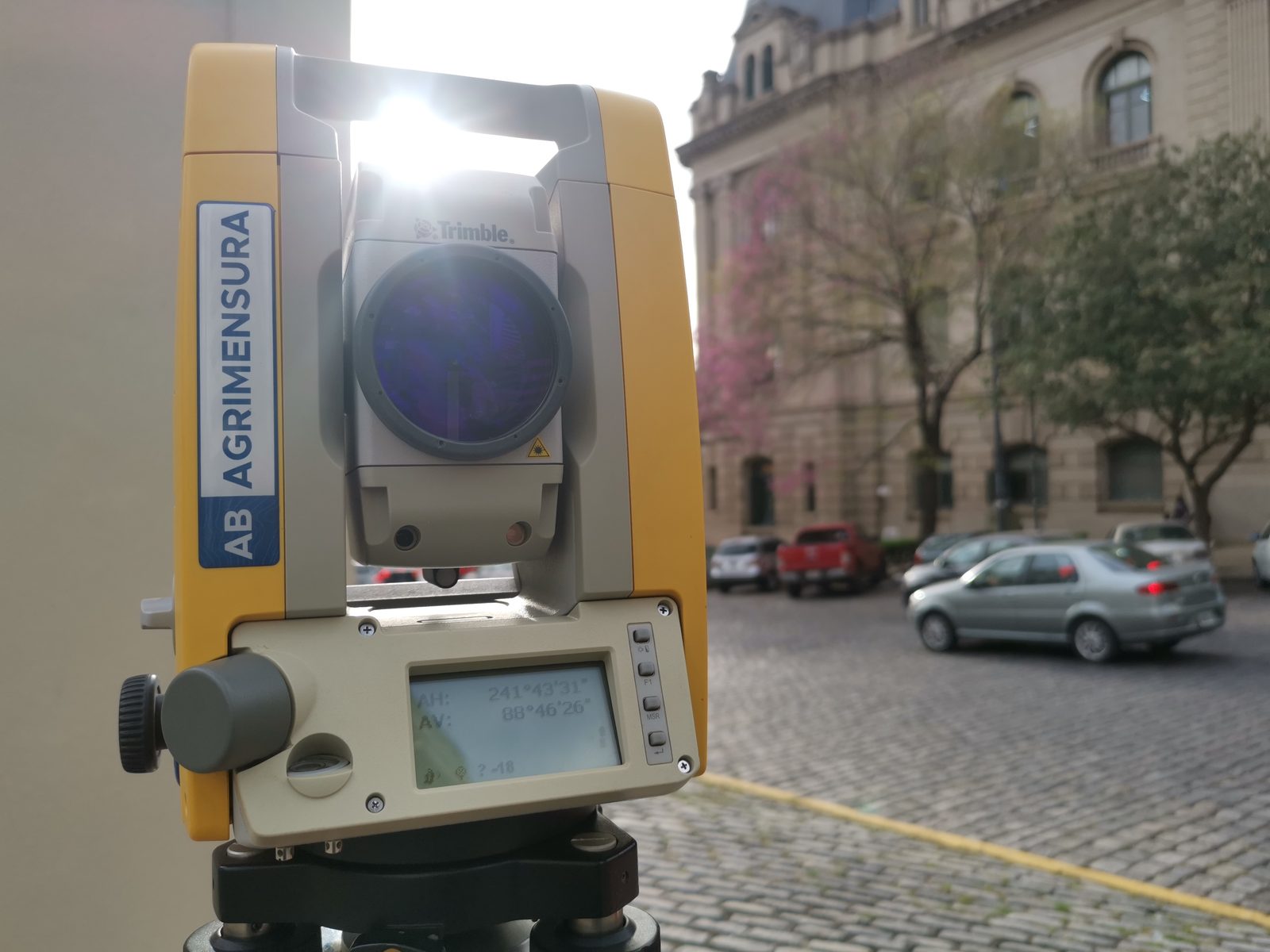 Estación total Trimble de AB Agrimensura en mensura urbana frente a edificio histórico